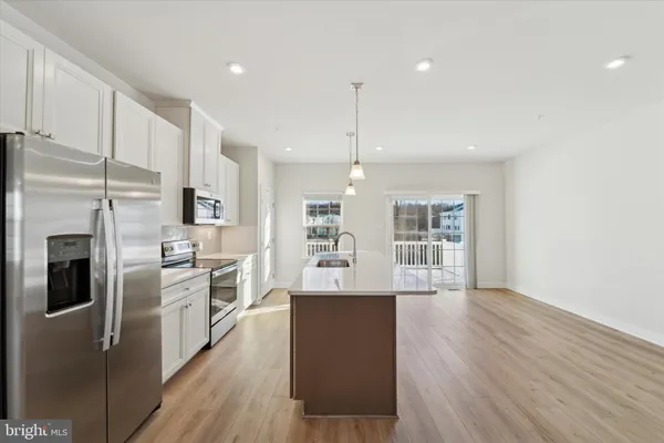 a kitchen with stainless steel appliances granite countertop a refrigerator a sink dishwasher a stove and white countertops with wooden floor