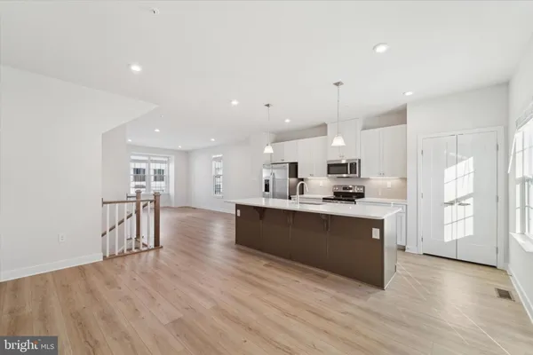 a large kitchen with stainless steel appliances kitchen island a large counter top and a refrigerator