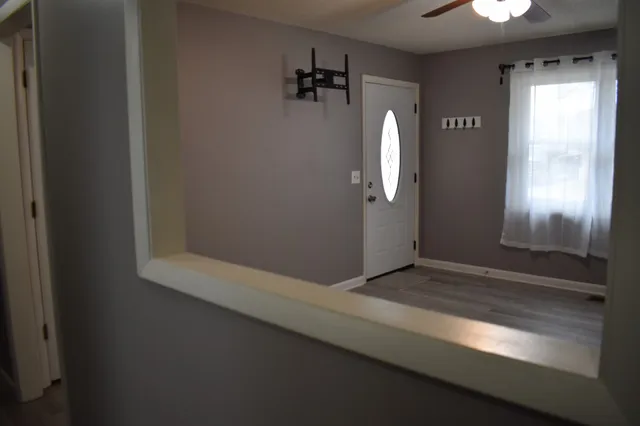 a view of an empty room with wooden floor and a window