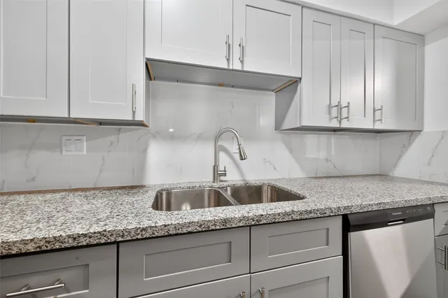 a kitchen with granite countertop white cabinets and a sink