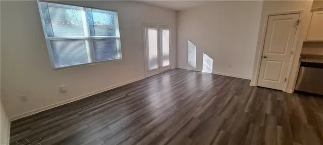 a view of an empty room with a window and wooden floor