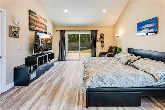 a bedroom with a large bed and a flat tv screen on dresser