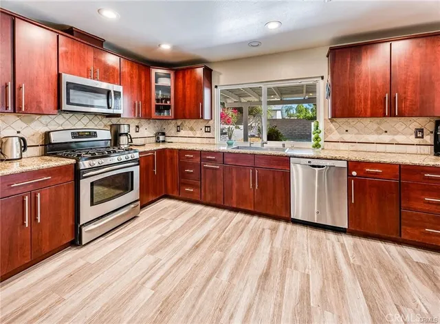 a kitchen with stainless steel appliances granite countertop wooden cabinets a sink a stove a microwave and cabinets