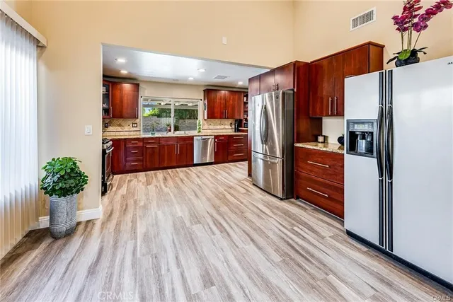 a kitchen with stainless steel appliances a refrigerator and a wooden floor