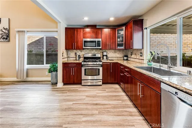 a kitchen with stainless steel appliances granite countertop wooden cabinets a sink and a stove