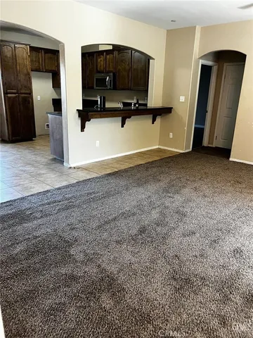 a view of an empty room with window and chandelier fan