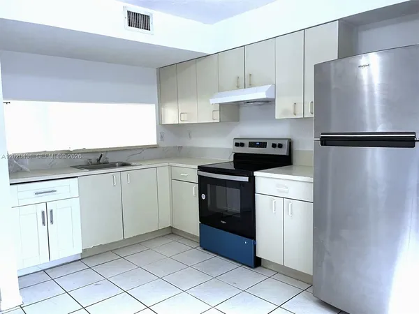 a kitchen with a refrigerator sink and cabinets