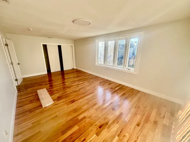 a view of an empty room with window and wooden floor