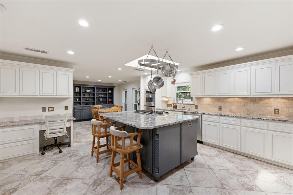 4000 Post Oak Road Flower Mound, TX 75022 - Photo 18 of 40 Main house - Kitchen with light stone countertops, white cabinets, decorative backsplash, crown molding, recessed lighting, and dining area off to the far left