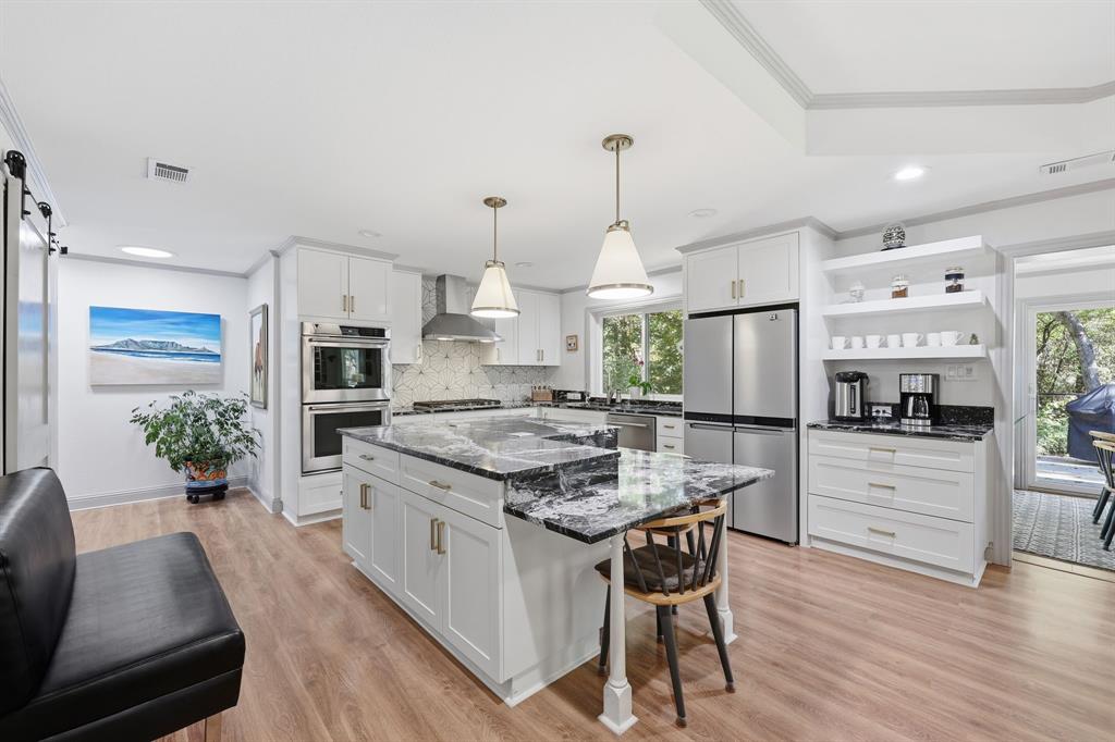 4000 Post Oak Road Flower Mound, TX 75022 - Photo 28 of 40 Guest house - Kitchen featuring a barn door pantry, open shelves, dark stone countertops, light wood-style floors, and pendant lighting
