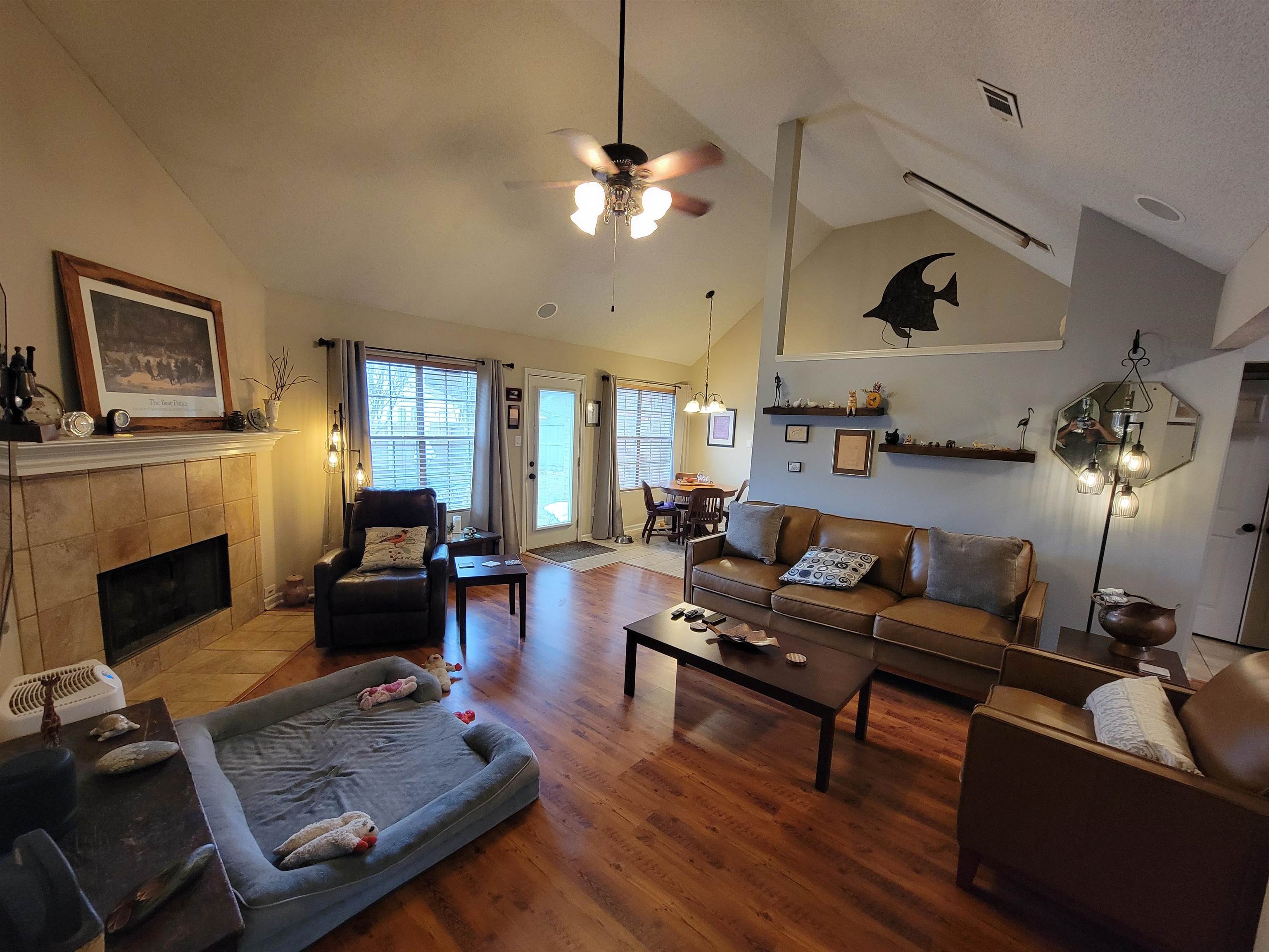 7926 Macon Road Cordova, TN 38018 - Photo 9 of 15 Living area with high vaulted ceiling, ceiling fan, a tiled fireplace, and wood finished floors