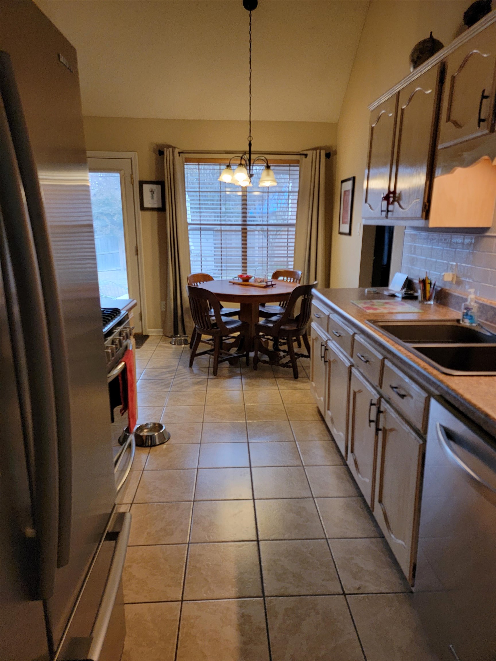7926 Macon Road Cordova, TN 38018 - Photo 10 of 15 Kitchen with appliances with stainless steel finishes, tasteful backsplash, lofted ceiling, light tile patterned floors, and hanging light fixtures