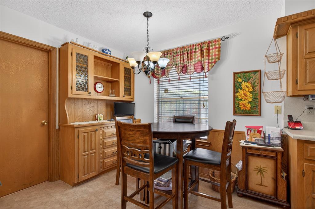 6010 Hunters View Lane Dallas, TX 75232 - Photo 11 of 28 Casual dining area featuring a round table, pendant light fixture, and wood-finish cabinetry with glass-front uppers