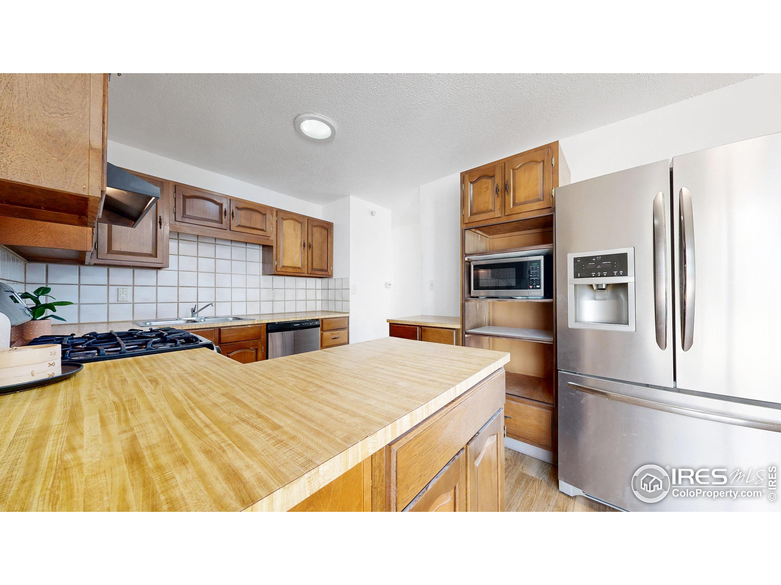 117 Fry Street Ault, CO 80610 - Photo 14 of 39 a kitchen with stainless steel appliances kitchen island granite countertop a refrigerator a stove and a sink