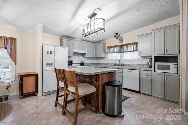 a kitchen with stainless steel appliances granite countertop a table chairs a refrigerator and cabinets
