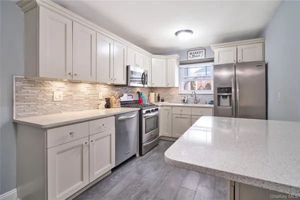 a kitchen with kitchen island granite countertop wooden cabinets a sink a stove a refrigerator and white cabinets