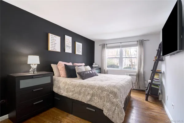a bedroom with a bed and a flat tv screen on the dresser