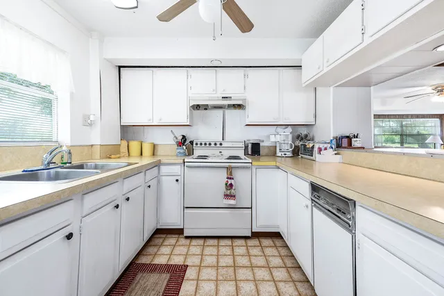 a kitchen with stainless steel appliances a sink a stove and white cabinets
