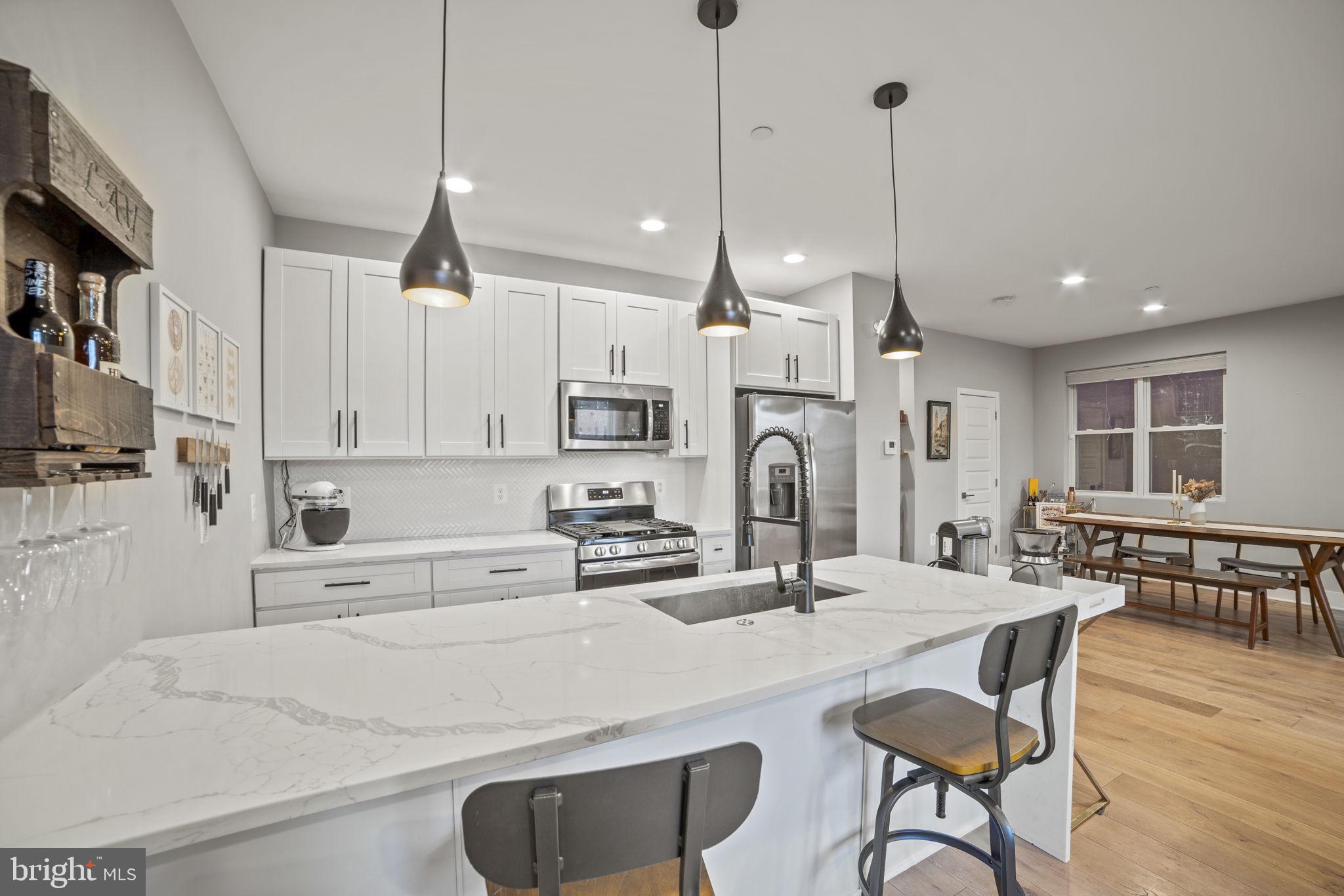1838 Providence Street Northeast, Unit 2 Washington, DC 20002 - Photo 5 of 17 a kitchen with stainless steel appliances kitchen island granite countertop a dining table chairs and white cabinets