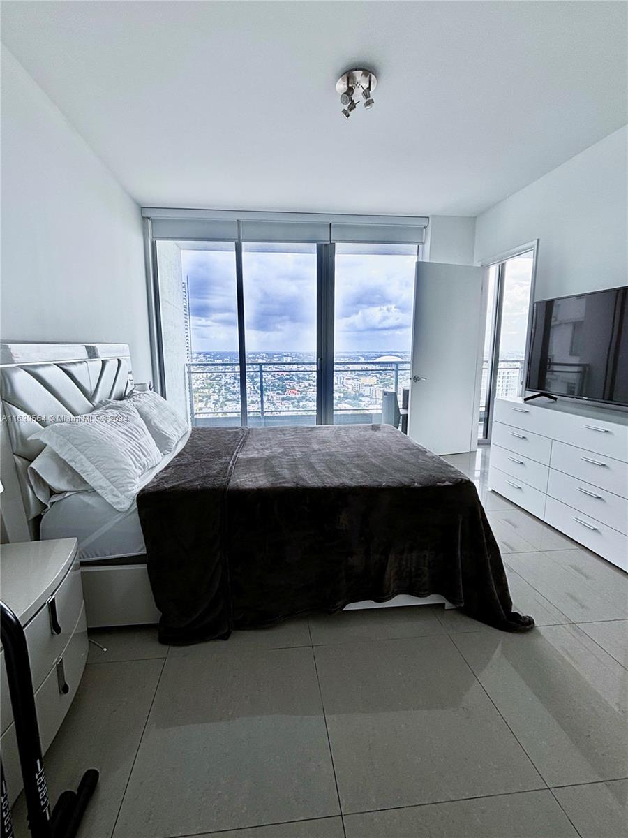 92 Southwest 3rd Street, Unit 4407 Miami, FL 33130 - Photo 11 of 21 a bedroom with a bed lamp and a large window
