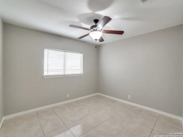 an empty room with a window and a fan