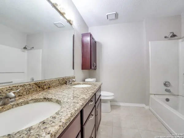a bathroom with a granite countertop sink and a bathtub