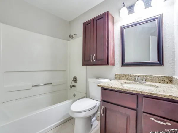 a bathroom with a granite countertop toilet sink and mirror