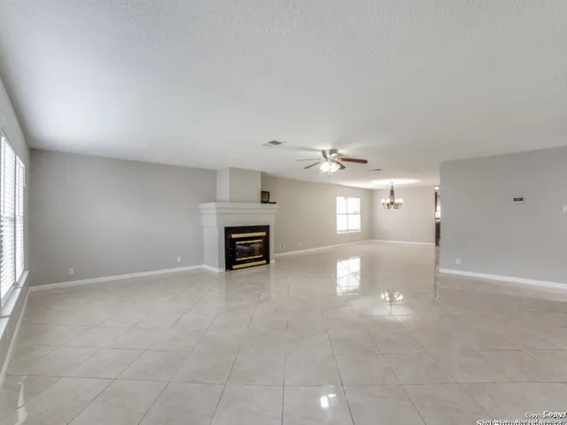 an empty room with chandelier fan and windows