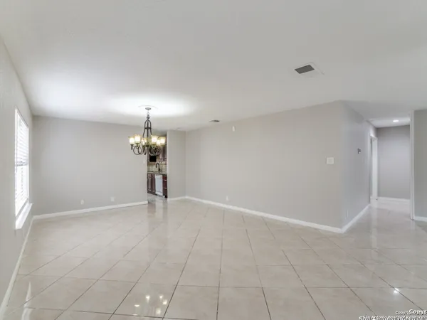 an empty room with chandelier and fan