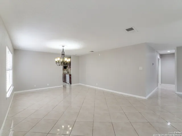 an empty room with chandelier and fan