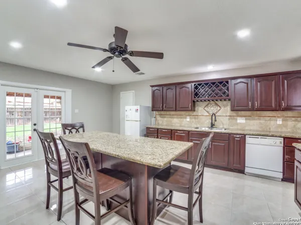 a kitchen with granite countertop a dining table chairs cabinets and stainless steel appliances