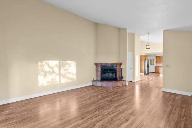 an empty room with wooden floor fireplace and windows