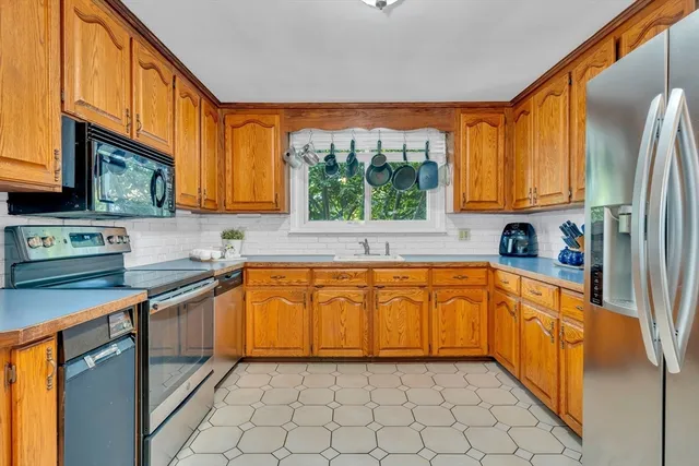 a kitchen with stainless steel appliances granite countertop a refrigerator a sink a stove and wooden cabinets