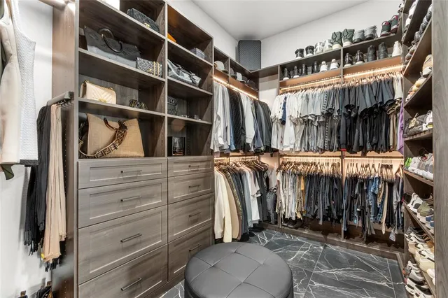 a view of walk in closet with clothes and shoes