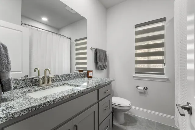 a bathroom with a granite countertop sink toilet and mirror