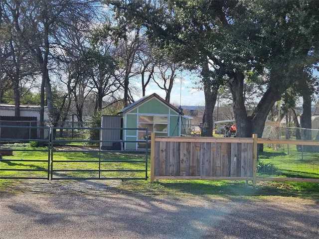 a view of a park with large trees and a wooden fence