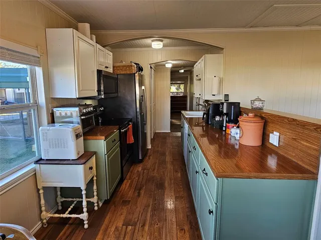 a kitchen with stainless steel appliances granite countertop a refrigerator a stove and a dining table with wooden floor