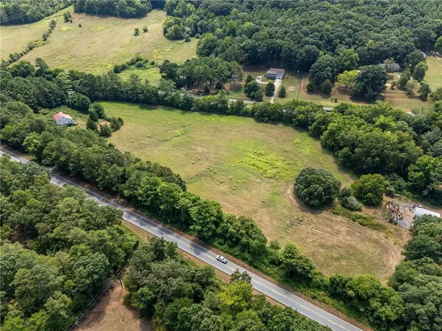 an aerial view of residential houses with outdoor space and trees all around