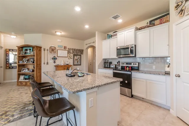 a kitchen with stainless steel appliances granite countertop a stove top oven a sink dishwasher and a refrigerator with wooden floor