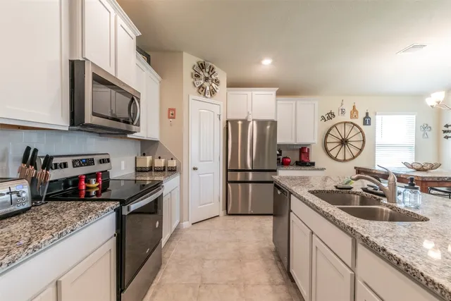 a kitchen with stainless steel appliances granite countertop a sink dishwasher a refrigerator a stove and a sink with wooden floor