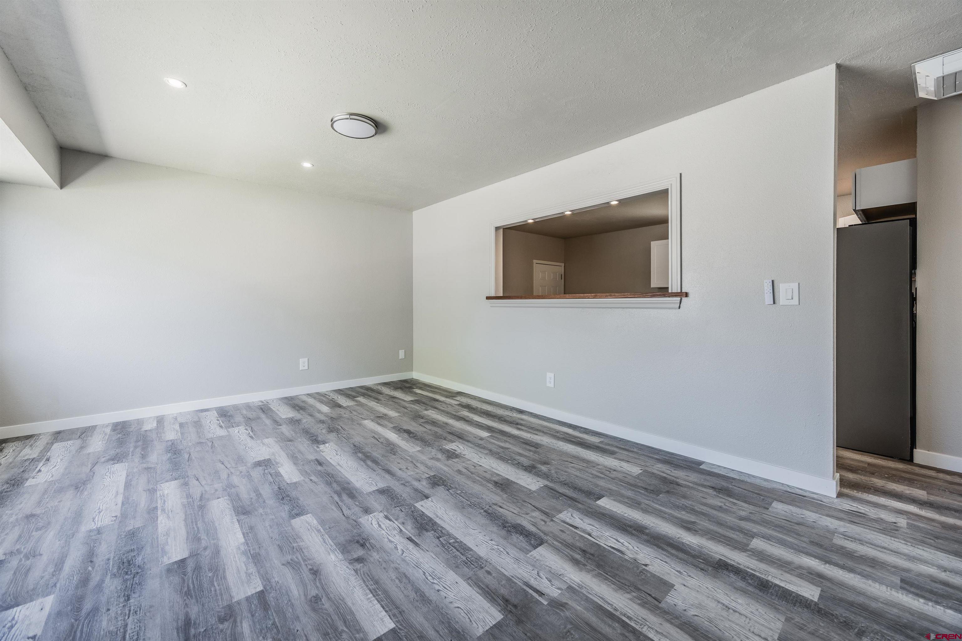 2130 Devon Street Montrose, CO 81401 - Photo 5 of 27 a view of an empty room with wooden floor and a kitchen
