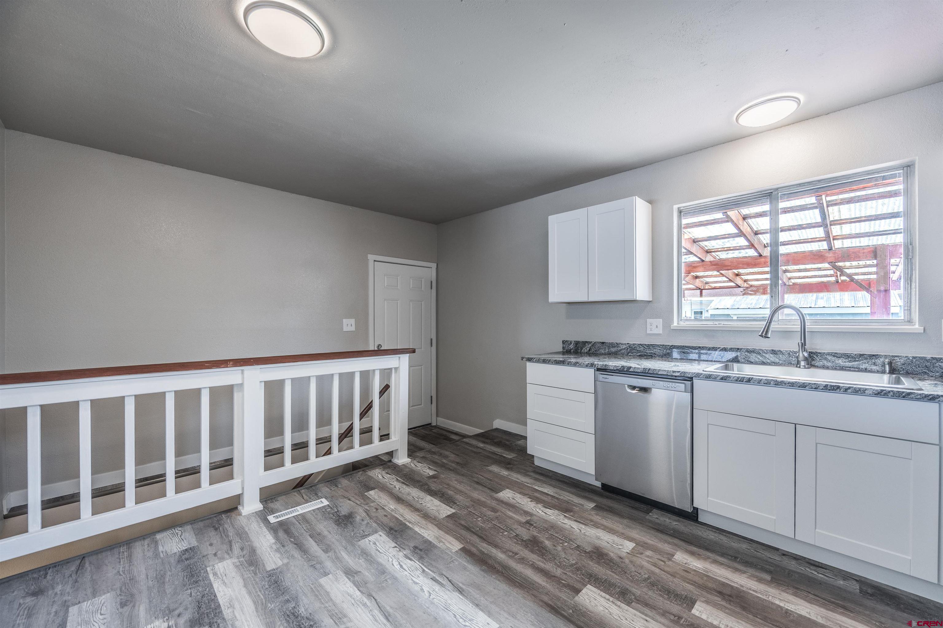 2130 Devon Street Montrose, CO 81401 - Photo 6 of 27 a kitchen with granite countertop a sink cabinets stainless steel appliances and a window