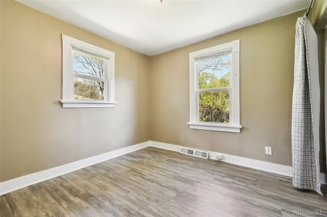 an empty room with wooden floor and a bathroom