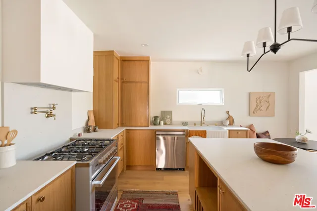 a kitchen with stainless steel appliances a stove a sink a dining table and chairs