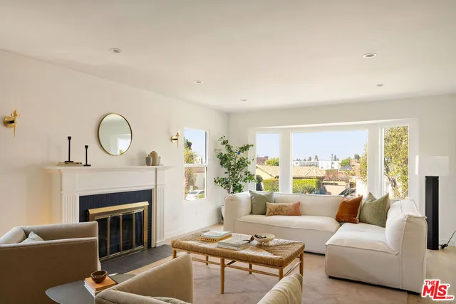 a living room with furniture a fireplace a rug and a window