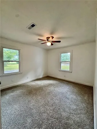 an empty room with windows and ceiling fan