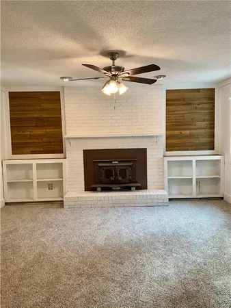 a view of a livingroom with a fireplace a ceiling fan and a fireplace