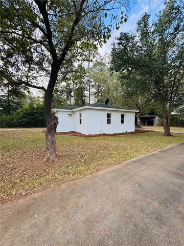 a view of a house with a yard and large trees