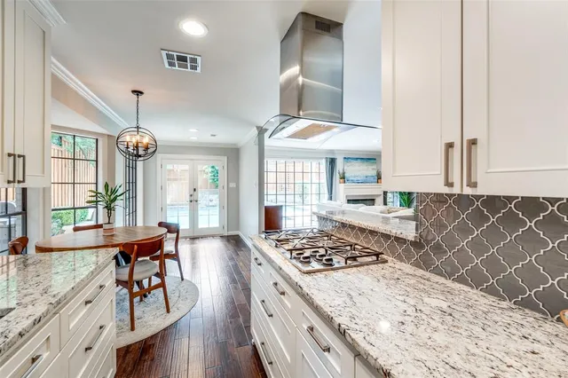 a kitchen with stainless steel appliances granite countertop a stove a sink dishwasher and a stove with wooden floor