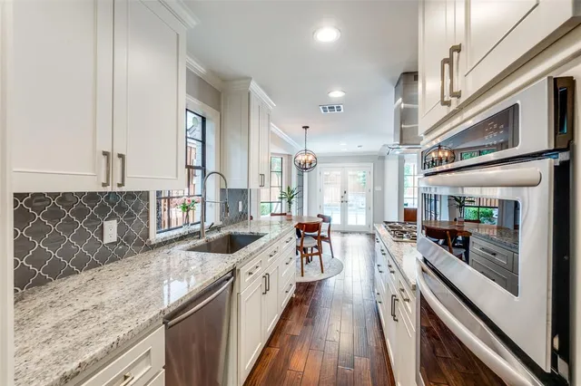 a view of a kitchen with stainless steel appliances granite countertop a lot of counter space and wooden floors